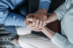 Close-up of several hands stacked together, symbolizing support and solidarity in a moment of care.